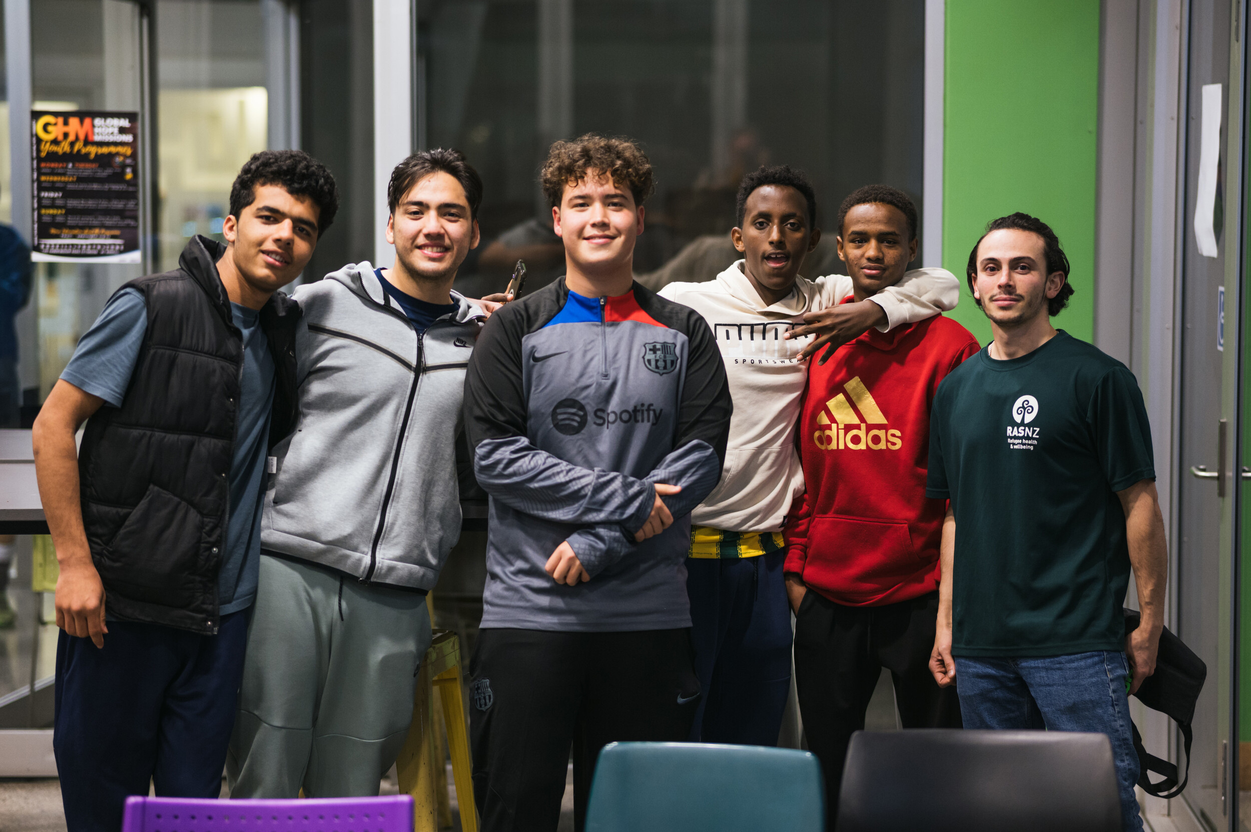 3.	A group photo of six young men smiling side by side with their arms around each other’s shoulders